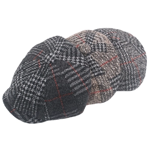 Close-up of three vintage wool newsboy caps in red, brown, and grey plaid patterns