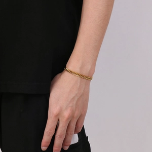 Close-up of a chunky golden Cuban link bracelet worn on a wrist for street style fashion