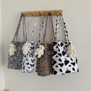 Detail showing four printed canvas tote bags with leopard and zebra patterns and bear charms