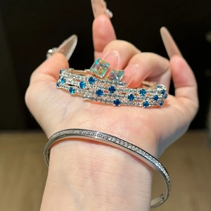 Three-layer silver bangle with cubic zirconia and blue rhinestones on woman hand