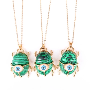 Detailed view of beetle-shaped green malachite pendants with blue evil eye charms