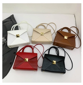 Flat lay of envelope handbags in five colors with faux crocodile texture and gold buckle