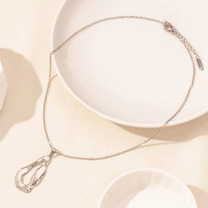 Macro detail of silver geometric pendant necklace with lobster clasp on ceramic plates