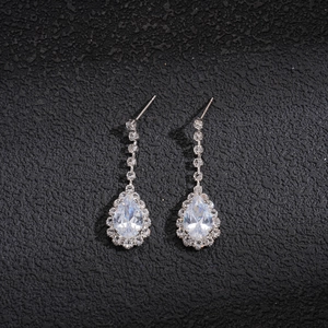 Detail shot of pear-cut diamond drop earrings in silver setting on dark textured surface
