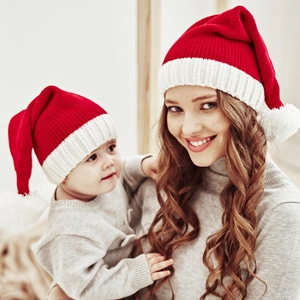 Close-up of mother and baby wearing red and white knitted Christmas pom-pom hats