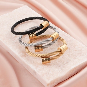 Detailed macro view of double-layer cable twist bracelets in black, gold, and silver finishes