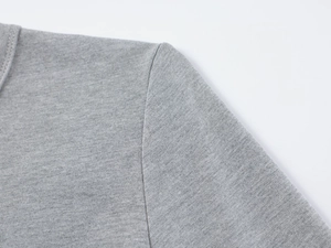 Détail de la couture d'épaule et texture du tricot sur un haut gris ajusté à manches longues