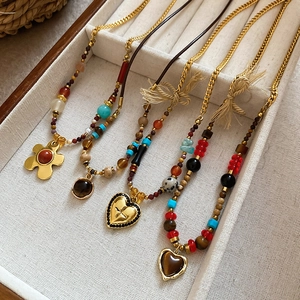 Detailed macro view of vintage tiger eye and turquoise necklaces on a white tray