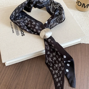 Detailed view of a black paisley silk scarf necklace with a silver matte dome buckle