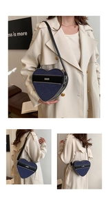 Detail view of heart-shaped crossbody bag in blue denim and black leather stitching