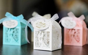 Detailed laser-cut wedding candy boxes in white, pink and blue with elegant ribbons
