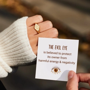 Detailed close-up of a gold s925 silver evil eye ring worn on a finger