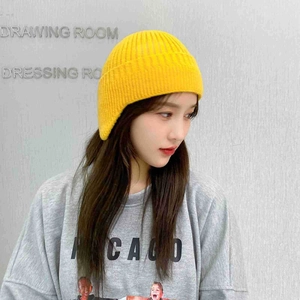 Detailed close-up of bright yellow knit beanie with fine texture on a model