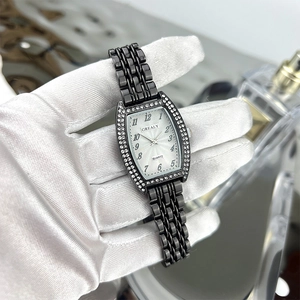 Close-up of barrel-shaped emerald style watch with rhinestones held by a gloved hand