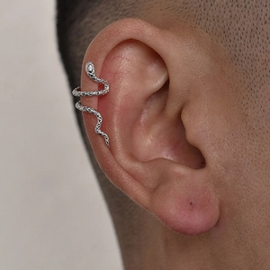 Close-up of silver snake ear cuff with scale texture on model's upper ear cartilage