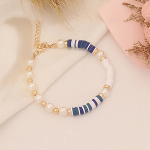 Detail of bohemian handmade bracelet with blue heishi beads and pearls on silk background