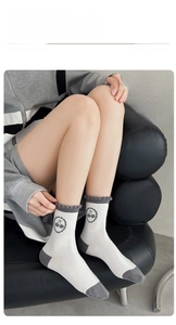 Détail de chaussettes en coton blanc avec bords volantés gris et motif cerise sur modèle