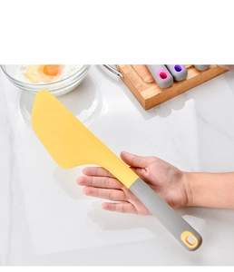 Detail of ergonomic handle and yellow silicone spatula on marble kitchen counter