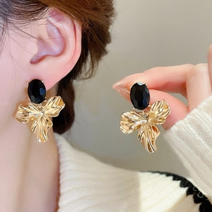 Detail of vintage-style gold ruffled flower earrings with oval black faceted stone inlay