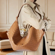 Close-up of brown woven leather hobo bag worn by model in a minimalist luxury setting