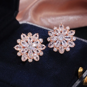 Detailed macro view of luxurious rose gold sunflower earrings with zircon in a blue box