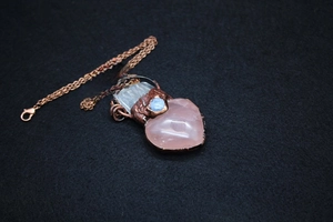 Detailed view of handmade rose quartz heart pendant with vintage copper wire wrapping