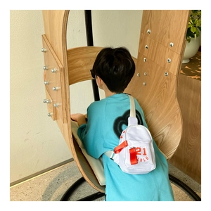 Vue arrière d'un enfant portant un sac de poitrine blanc avec lettrage orange pour le style