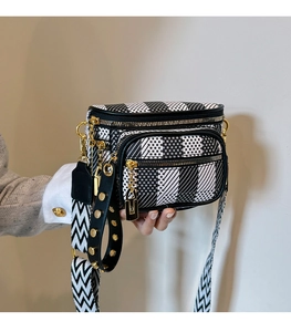 Close-up of black and white geometric pattern saddle bag with gold metal hardware and wide strap