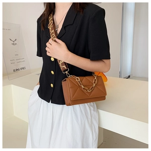 Detailed side view of brown quilted small crossbody bag with gold chain and wide logo strap