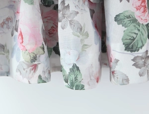 Makrodetail des Kleidsaums mit rosa Rosenmuster und gewebter Textur des floralen Stoffes