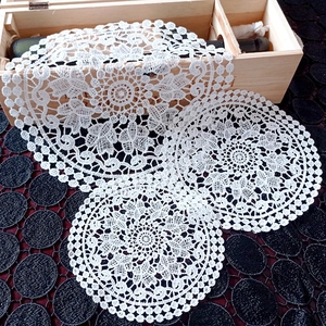 Detailed macro view of white lace embroidered coasters with intricate circular patterns