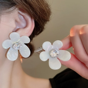 Macro shot of elegant white flower stud earrings with shimmering petals and zircon centers