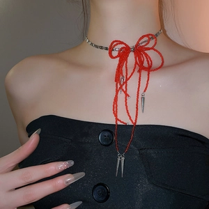 Macro view of red bow beaded choker necklace with silver tassels and cone pendants