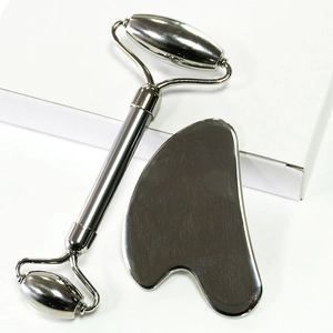 Stainless steel facial massage set with double-headed roller and gua sha on white box