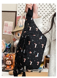 Detail of black crossbody bag featuring cartoon dachshund print and dual zipper closure