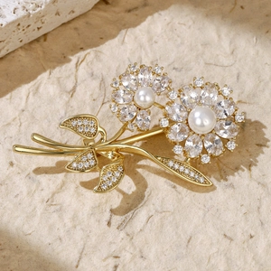 Macro shot of gold floral brooch with white pearls and sparkling cubic zirconia stones