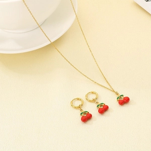 Detailed view of red cherry pendant jewelry set with golden chain and green stems