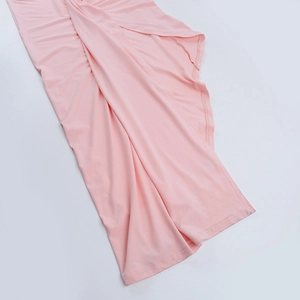 Détail de la robe en maille rose avec un ourlet irrégulier et des plis drapés fluides
