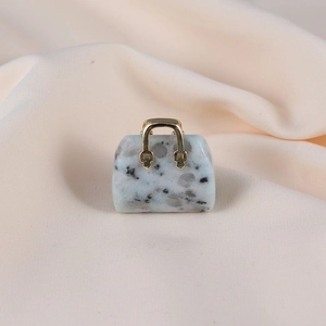 Macro shot of stone handbag pendant with white and grey marble texture and gold handle