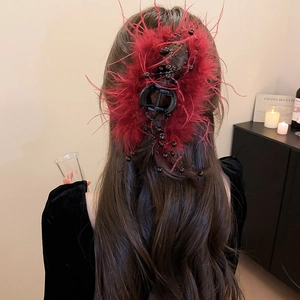Macro view of large red feather hair claw clip with black beads on elegant updo hair