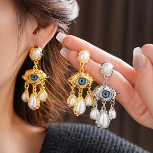 Detailed view of vintage eye-shaped earrings with blue eyeballs and hanging pearls