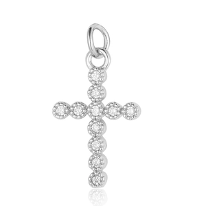 Macro close-up of a silver cross pendant with small zircon stones and light reflection