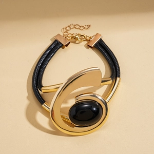 Detailed shot of a gold oval metal frame bracelet with a black gemstone inlay