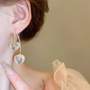 Detail of long cherry drop earrings with gold metal stems and clear glass spheres