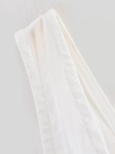 Detail of white summer top featuring delicate lace trim and pleated cotton fabric texture
