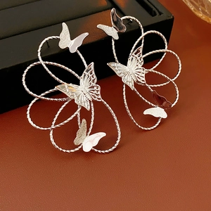 Macro shot of silver-colored butterfly earrings featuring intricate layered metal coil design