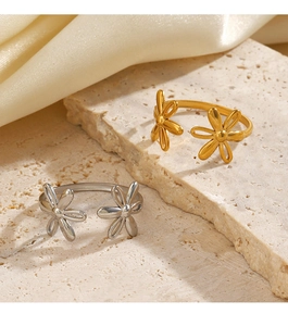Detail view of gold and silver flower rings on beige stone and silk fabric background
