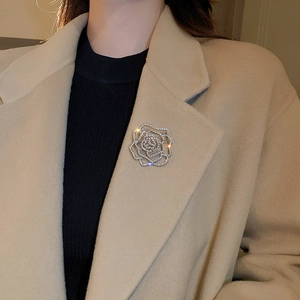Macro shot of silver-tone hollow rose brooch with sparkling crystals on a beige coat