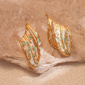 Artistic gold leaf earrings with green enamel splash on natural stone background