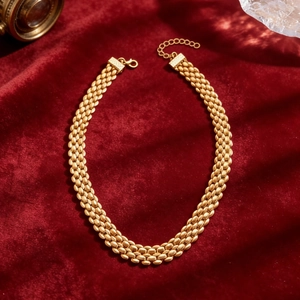 Detailed view of a gold triple-row link chain necklace on a luxury red velvet background